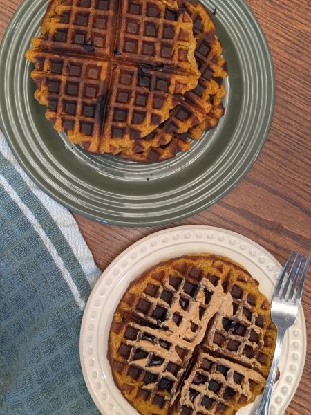 vegan pumpkin protein waffles topped with peanut butter and maple syrup