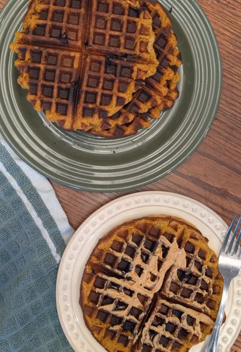 vegan pumpkin protein waffles topped with peanut butter and maple syrup