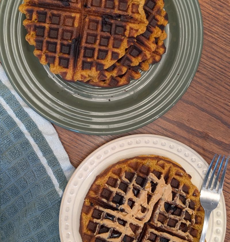 vegan pumpkin protein waffles topped with peanut butter and maple syrup